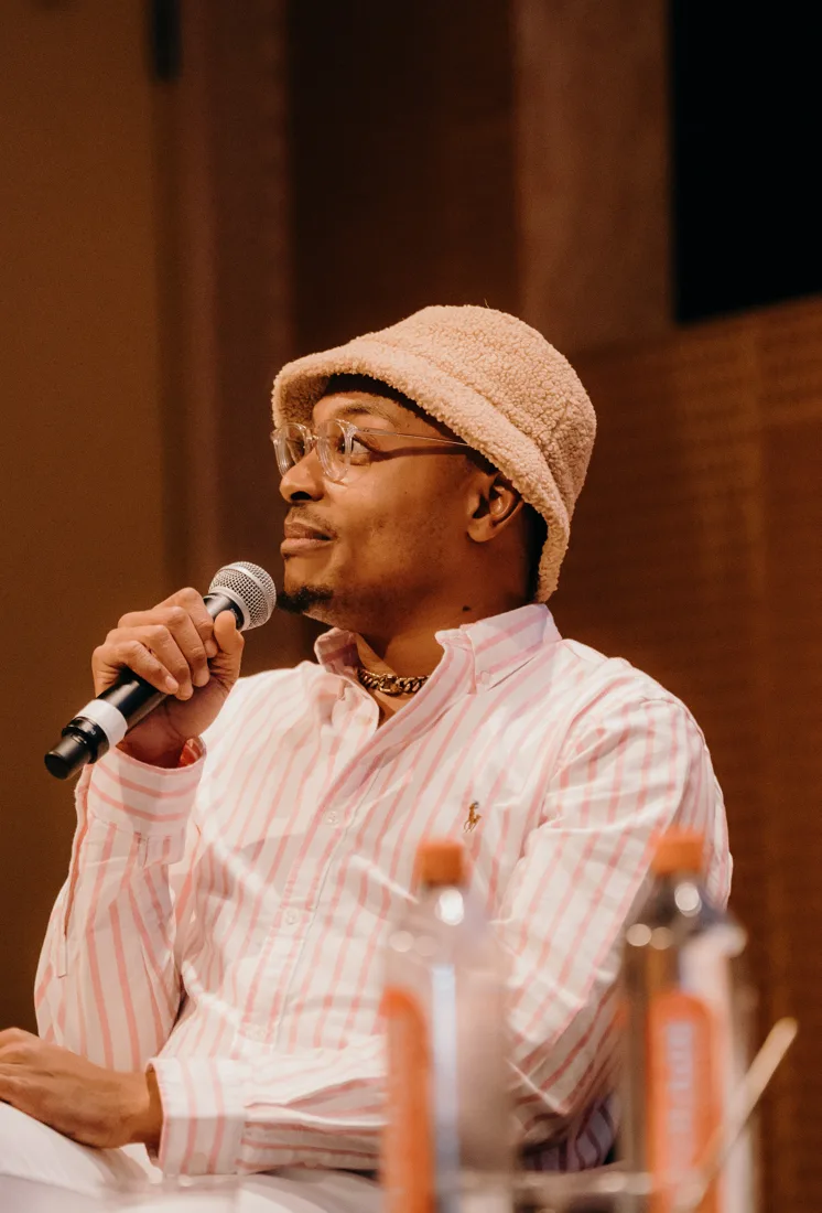 D speaking into a microphone during a panel discussion